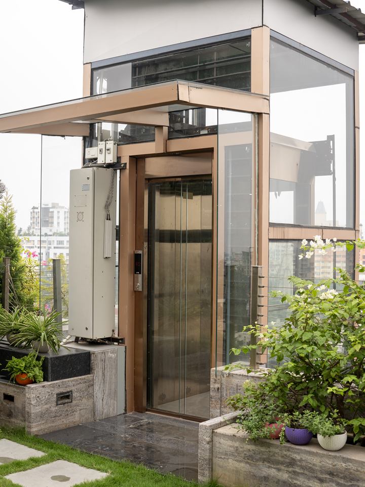 Rooftop home lift with full-glass automatic doors in a terrace garden