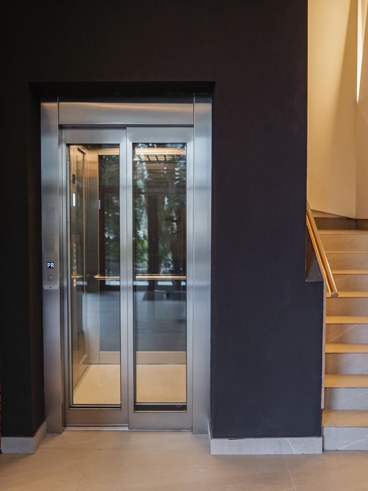 Home lift with automatic telescopic doors beside a staircase