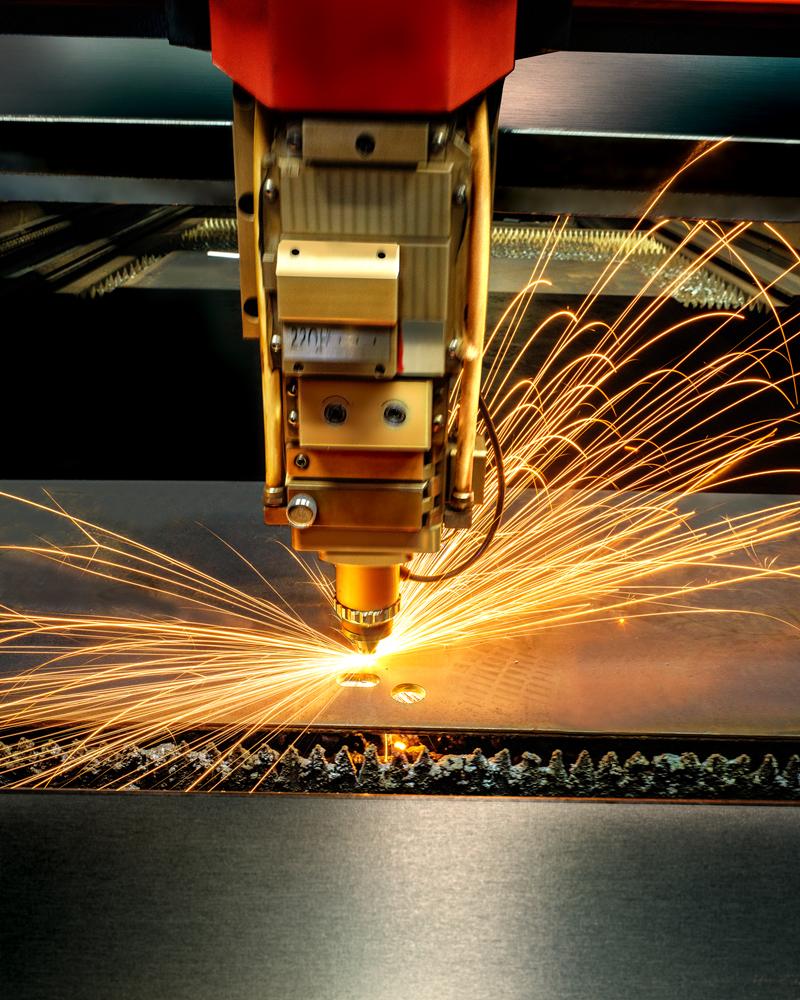 Laser cutting head throwing sparks over a steel sheet