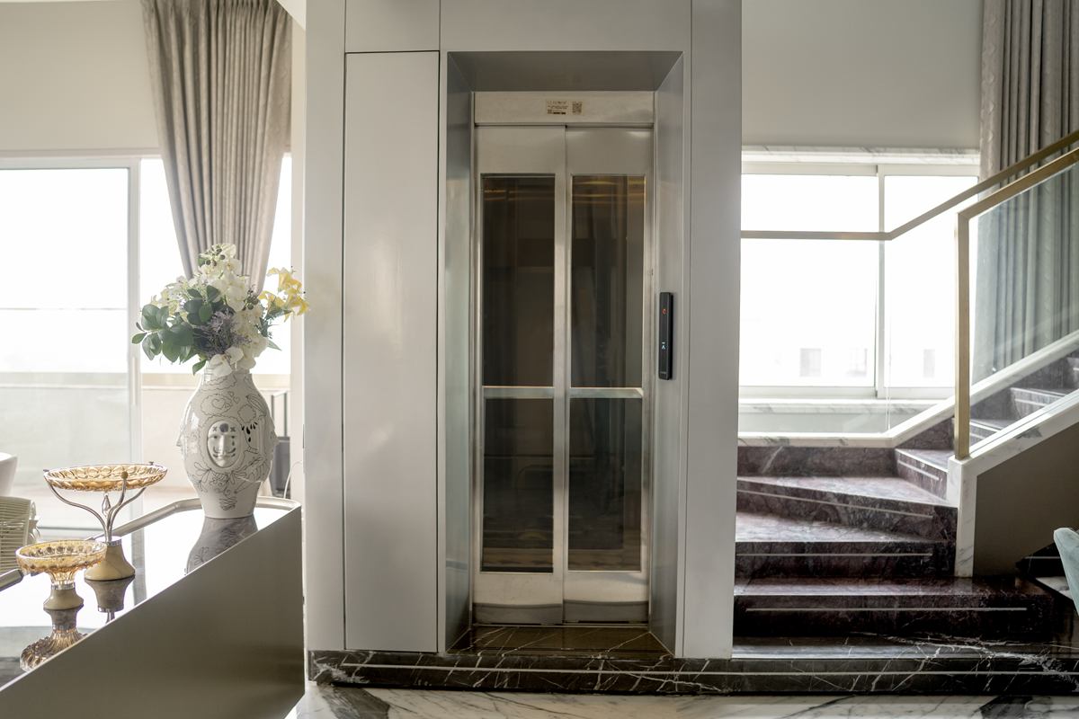 Home elevator installed beside a marble staircase in a villa