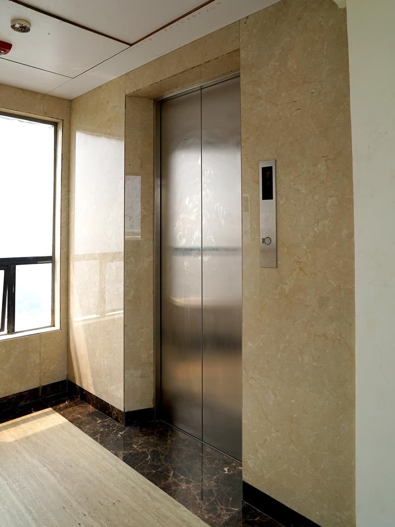 Lift entrance in a residential lobby with stone walls